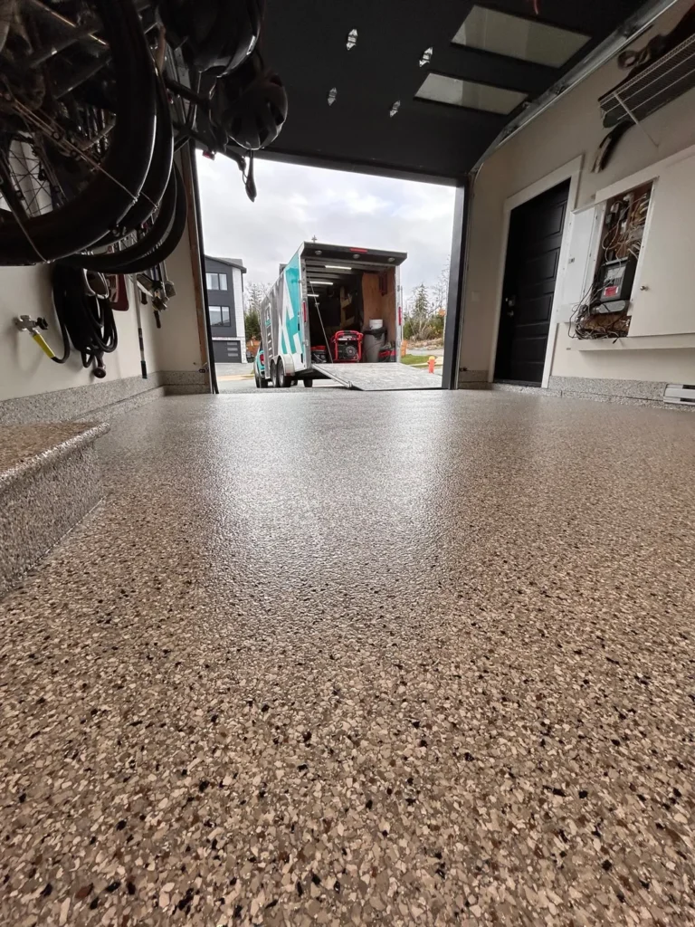 Coyote flake garage floor with coated baseboards and stairs in Timberlea